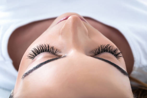 Girl with extended silk eyelashes lies in a beauty studio stock photo