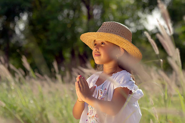 Girl with hat has its hands in prayer position stock photo