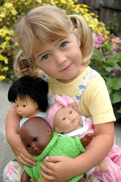 Girl with multi=ethnic dolls Three year old girl playing with Asian, African American and Caucasian dolls doll stock pictures, royalty-free photos & images