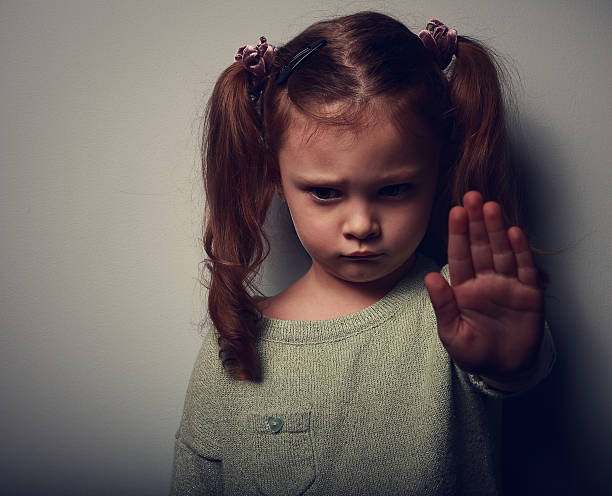 Girl with pigtails in shadow with hand up in stop gesture stock photo