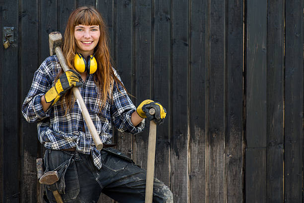 Girl with sledgehammer Young scandinavian red haired girl in construction worker clothes standing with a shovel and a hammer smiling to the camera in front of a barn in Sweden swedish girl stock pictures, royalty-free photos & images
