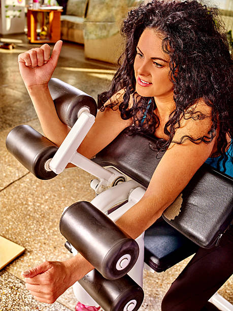 Girl workout on bicep curl machine in sport gym Girl workout on bicep curl machine in sport gym. Top view. tricep curl machine stock pictures, royalty-free photos & images