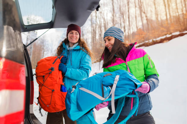 freundinnen packen einen kofferraum - auto packen für den urlaub winter stock-fotos und bilder