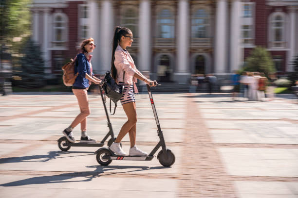 girlfriends riding e-scooters in the city - trotinetes imagens e fotografias de stock