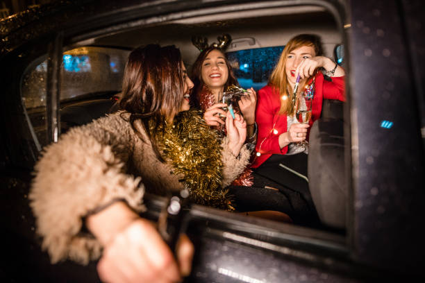 Girls celebrating in taxi, on their way to the party Three beautiful girls in taxi car, sitting on back seat on their way to the party. Celebrating, laughing, drinking champagne new years eve girl stock pictures, royalty-free photos & images