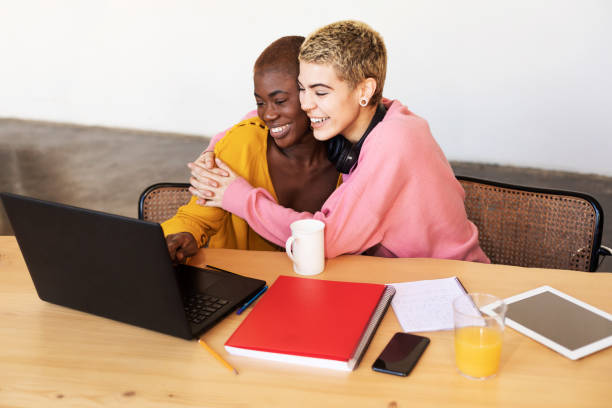 Girls drinking coffee and shopping online on laptop stock photo
