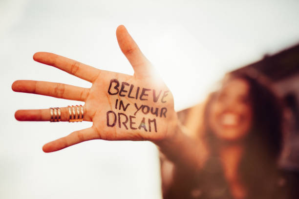 Girl's hand with "Believe in your Dreams" written on it Closeup of a teenage girl's hand with the phrase "Believe in your Dreams" written in permanent marker on it, with her smiling face blurred in the background Believe in Your Dreams stock pictures, royalty-free photos & images