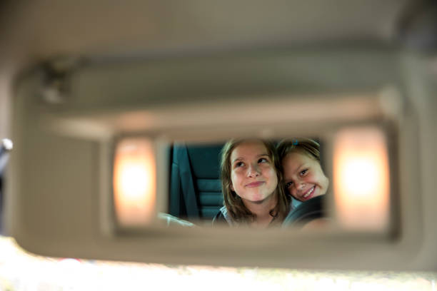 Girls in rear-view mirror Two little girls in a rear-view mirror in a car. Lights on the mirror. big smile emoji stock pictures, royalty-free photos & images