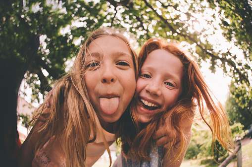 Girls laughing and pulling faces at the camera in park stock photo