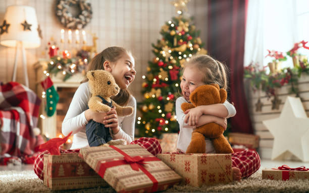 meisjes openen kerstcadeaus - speelgoed stockfoto's en -beelden