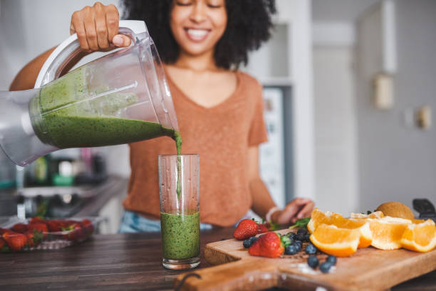 Give your body the good stuff Shot of a young woman making a healthy smoothie at home smoothie stock pictures, royalty-free photos & images
