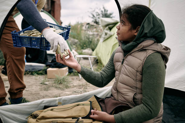 Giving Canned Food To Refugee Girl stock photo