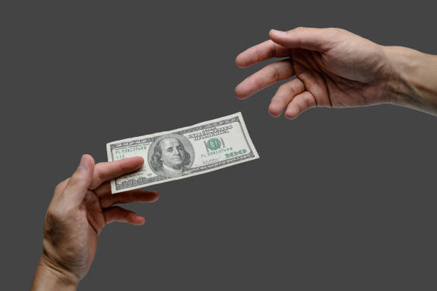 giving one hundred dollar bill to other hand isolated background stock photo