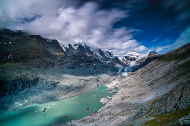 glacier with lagoon and pasterze in austrian mountains showing effects of climate change Großglockner glacier with glacial lake in austrian mountains on sunny summer day with clouds, long exposure hohe tauern range stock pictures, royalty-free photos & images