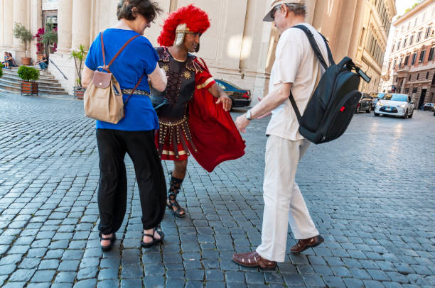 Gladiator impersonator near Colosseum entertains tourists to take photos with them stock photo