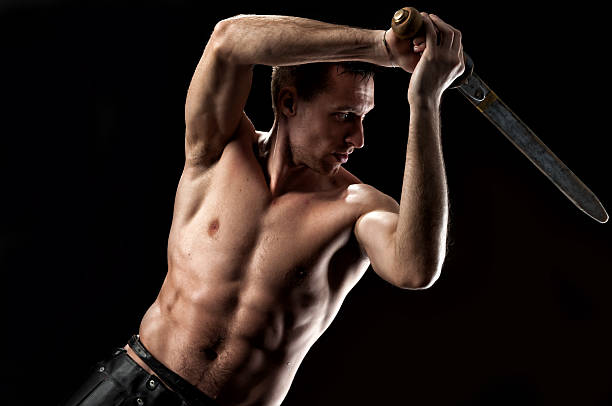 Gladiator warrior with naked torso and sword isolated on black stock photo