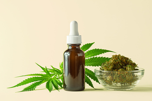 Glass Bottle Of CBD Or THC Oil With Hemp Or Medical Cannabis Plant Picture