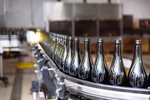 Glass bottles on the automatic conveyor line at the champagne or wine factory. Plant for bottling alcoholic beverages stock photo