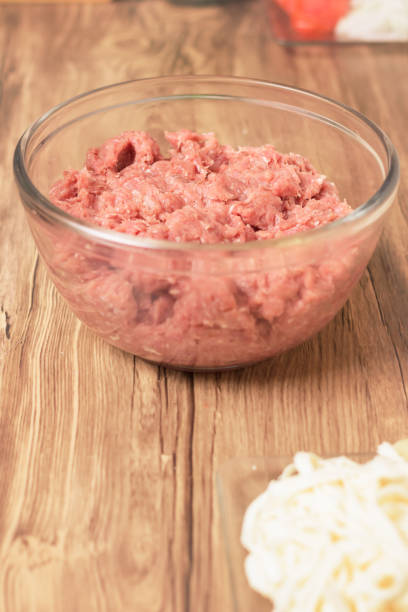 glass bowl with minced raw beef or beef pork on wooden table in the comfort of home stock photo
