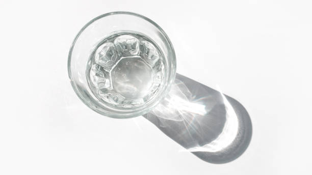 Glass cup with water with hard shadows on a white background. The concept of minimalism. stock photo