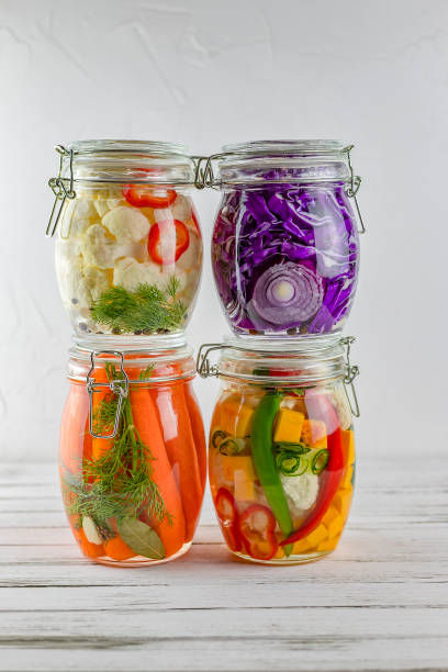glass jars of fermented red cabbage, cauliflower, cucumbers, onions, carrots, vegetables on a light background. fermentation is a source of probiotic glass jars of fermented red cabbage, cauliflower, cucumbers, onions, carrots, vegetables on a light background. fermentation is a source of probiotics. fermenting stock pictures, royalty-free photos & images