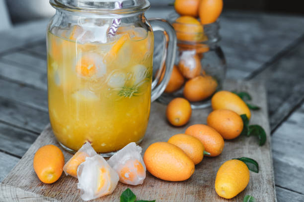 Glass jars of orange juice with ice and kumquat  on wooden table Glass jars of orange juice with ice and kumquat  on wooden table kumquat stock pictures, royalty-free photos & images