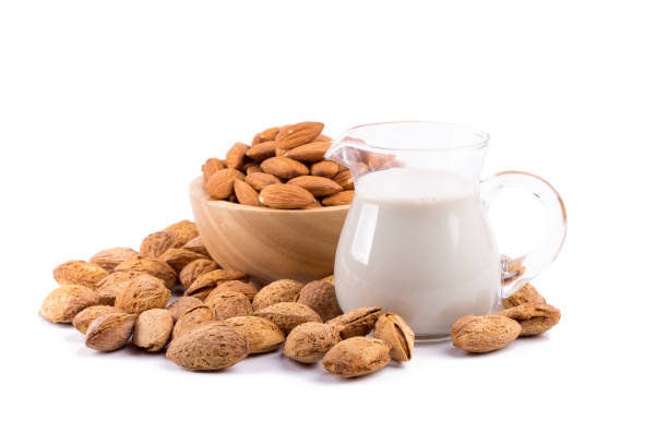 Glass of Almond milk with a heap of almonds on white background stock photo