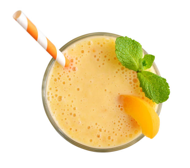 Glass of apricot milkshake Glass of apricot milkshake or smoothie with drinking straw and mint leaves  isolated on white background, top view mango smoothie stock pictures, royalty-free photos & images