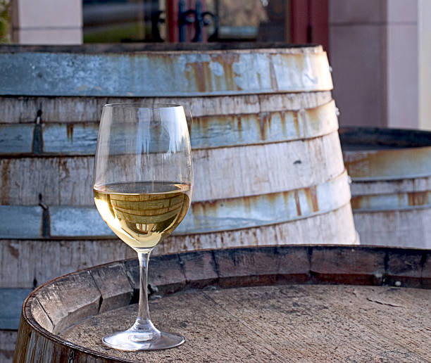 A glass of Chardonnay sitting on a barrel stock photo
