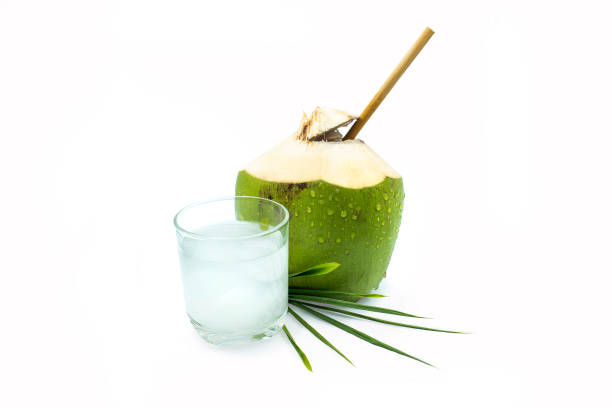 A glass of coconut water with green coconut on a white background.