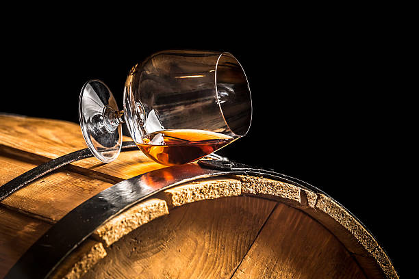 Glass of cognac on the old wooden barrel stock photo