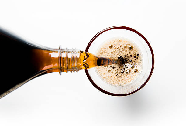 A glass of cola being poured into a glass stock photo
