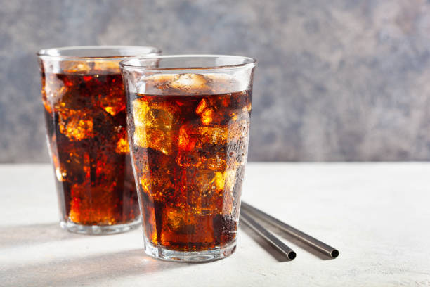 glass of cold cola soft drink with ice on wooden background stock photo