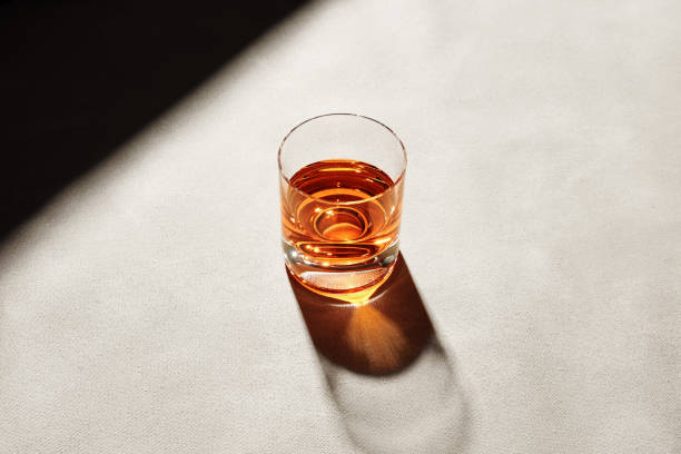 Glass of elegant straight or neat whiskey on a bar counter with dark moody atmosphere. Drink art stock photo