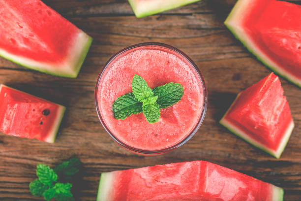 A glass of fresh watermelon juice on a wooden board background stock photo