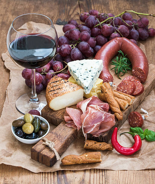 Glass of red wine, cheese and meat board, grapes,fig Glass of red wine, cheese and meat board, grapes,fig, strawberries, honey and bread sticks  on rustic wooden table, white background, selective focus muenster cheese stock pictures, royalty-free photos & images