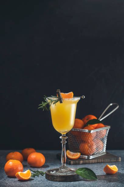 Glass of refreshing Tangerine Margarita cocktail served on dark gray table surface surround of fresh tangerine fruit stock photo