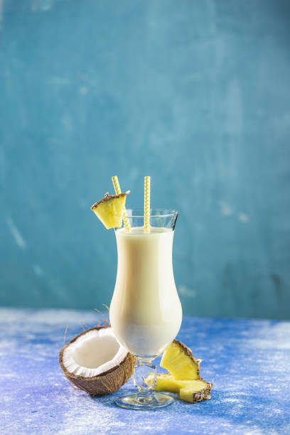 Glass of tasty Frozen Pina Colada Traditional Caribbean cocktail decorated by slice of pineapple, served on blue concrete background stock photo