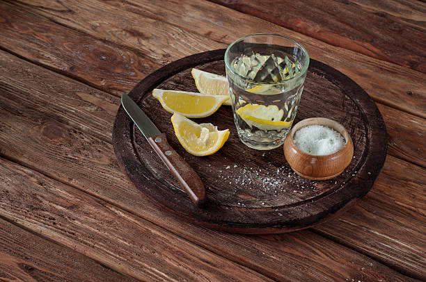 glass of tequila with lemon slices and salt glass of tequila with lemon slices, salt and a knife on a wooden background. Top view. Copy space. Free space for text. Toned vintage style bar drink establishment photos stock pictures, royalty-free photos & images
