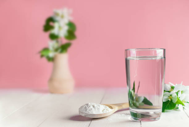 glass of water, spoon with collagen powder white flowers glass of water, spoon with collagen powder white flowers on pink background collagen stock pictures, royalty-free photos & images