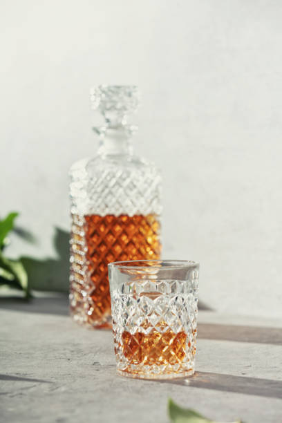Glass of whiskey with ice cubes and carafe close up stock photo