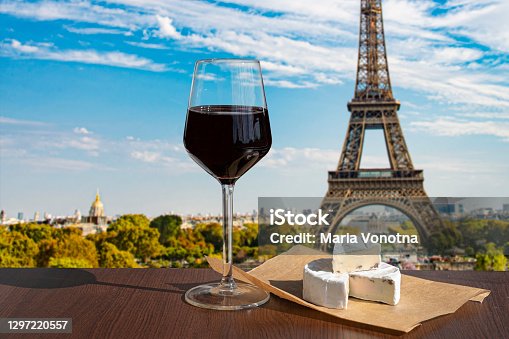 istock Glass of wine with brie cheese on Eiffel tower and Paris skyline background 1297220557