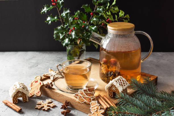Glass teapot with blossoming tea and tea cup on grey table with Christmas gingerbread cookies. Glass teapot with blossoming tea and tea cup on grey table with Christmas gingerbread cookies. Christmas holiday tea ceremony. infused photos stock pictures, royalty-free photos & images