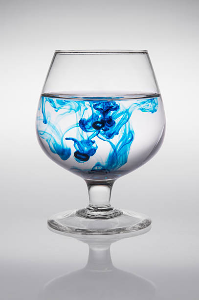 glass with blue ink that creates waves of color stock photo