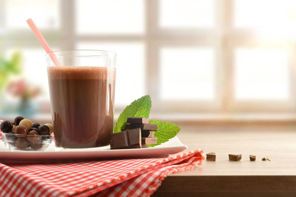 Glass with chocolate milkshake on plate with tablecloth front isolated stock photo