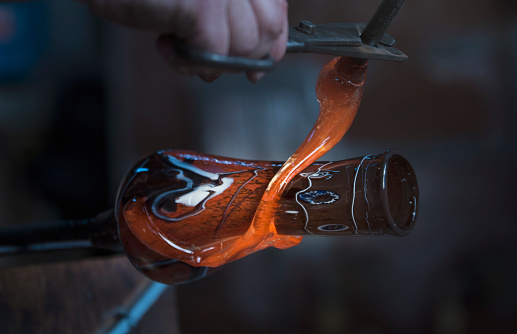 Glassblowing worker cutting liquid glass