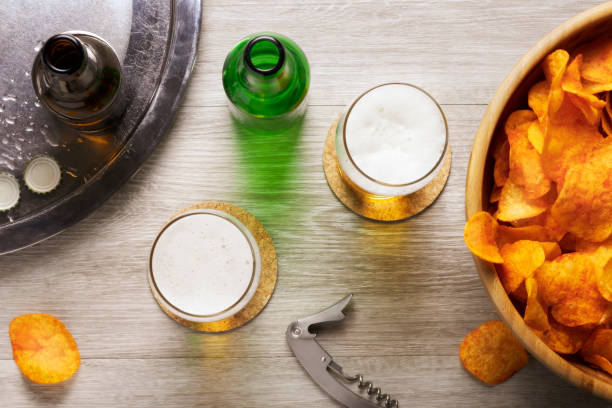 glasses of beer, beer bottles and crisps and a bottle opener, top view, flat lay stock photo