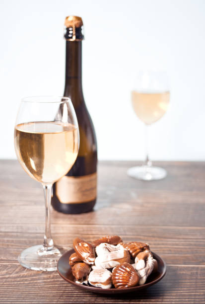 Glasses of champagne or white grape wine with plate of chocolates, bottle on the background stock photo