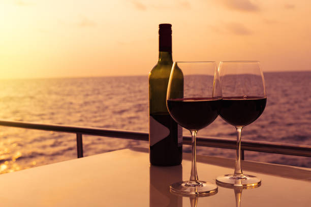 Glasses, red wine and tropical sunset with sea background, nobody. stock photo