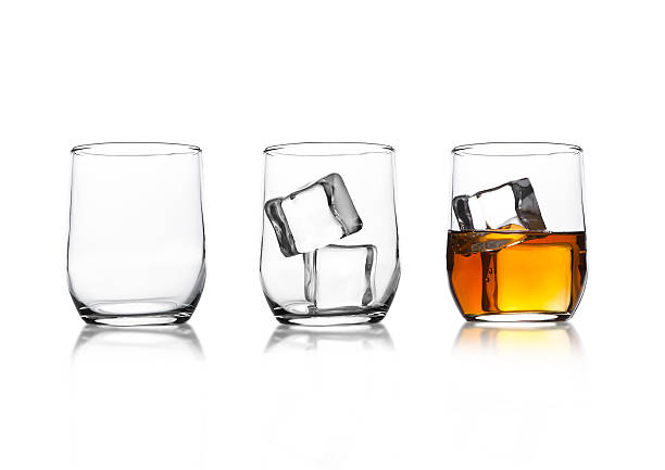 Glasses with whiskey and ice cubes and empty glass Glasses with whiskey and ice cubes and empty glass with reflection on white background highball glass stock pictures, royalty-free photos & images